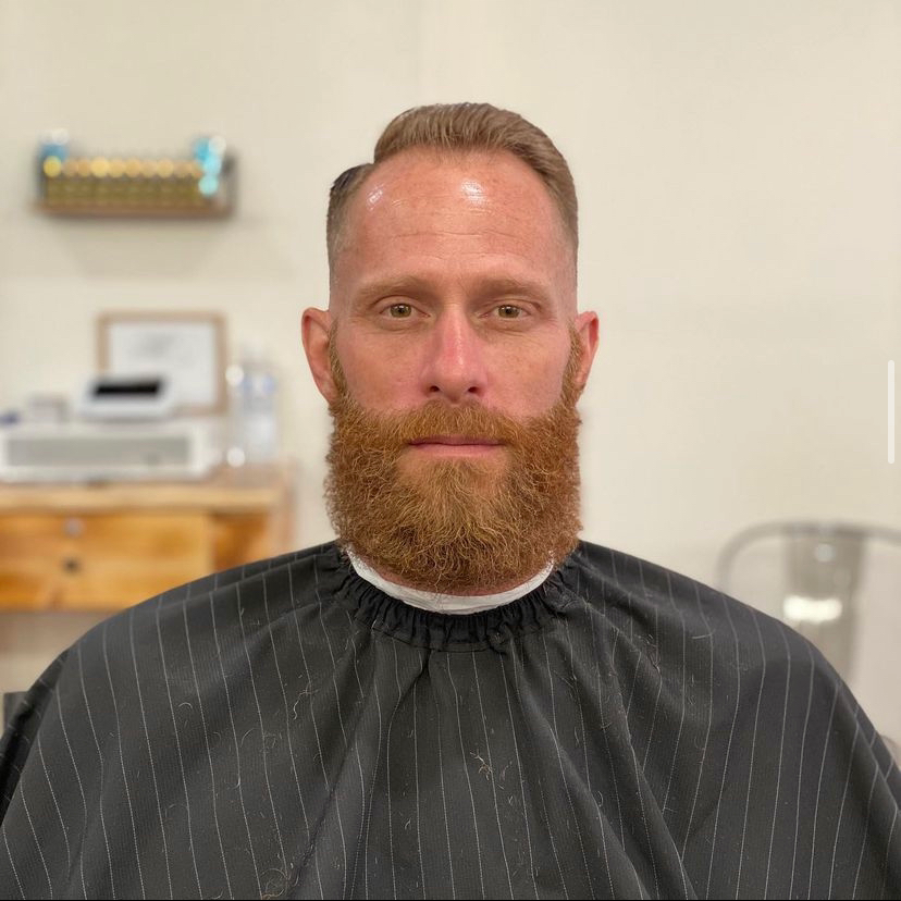 Classic side part haircut with a full red beard trim at To the Nines Barbershop in Tempe