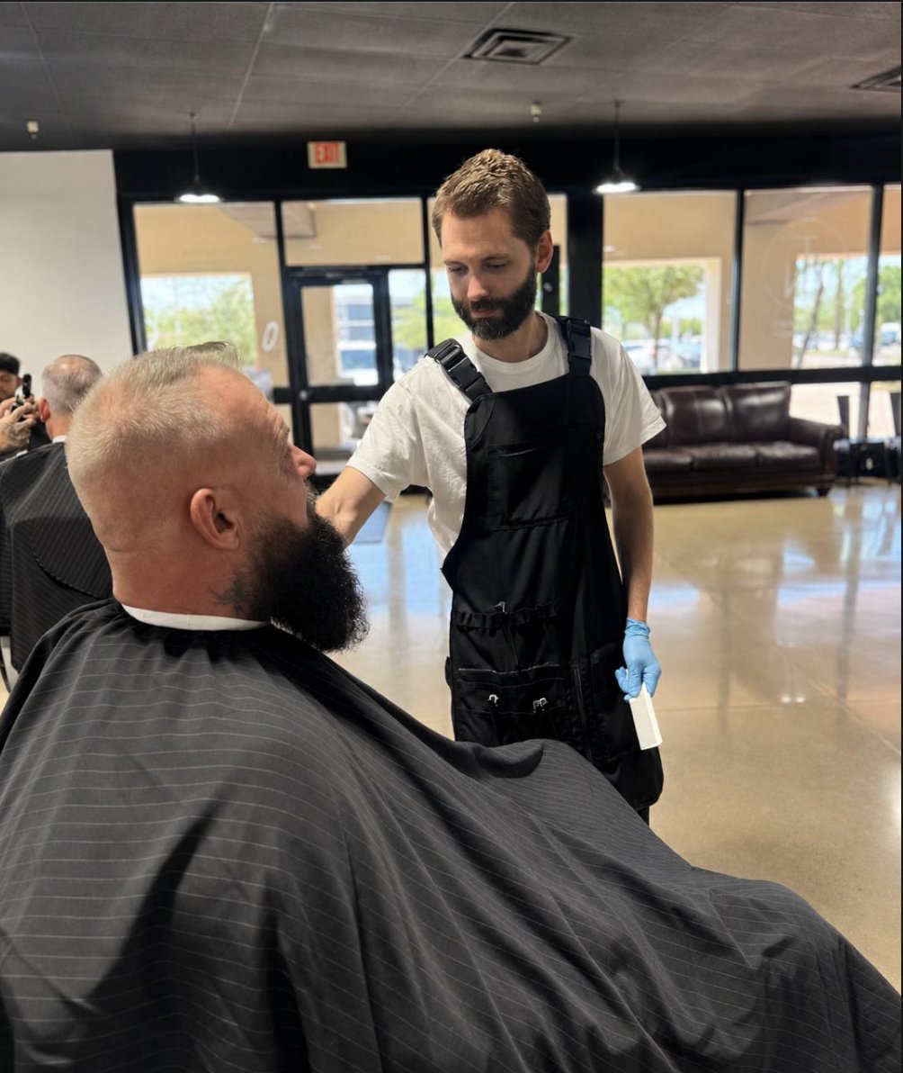 Barber trimming a client's full beard at To the Nines Barbershop in Tempe