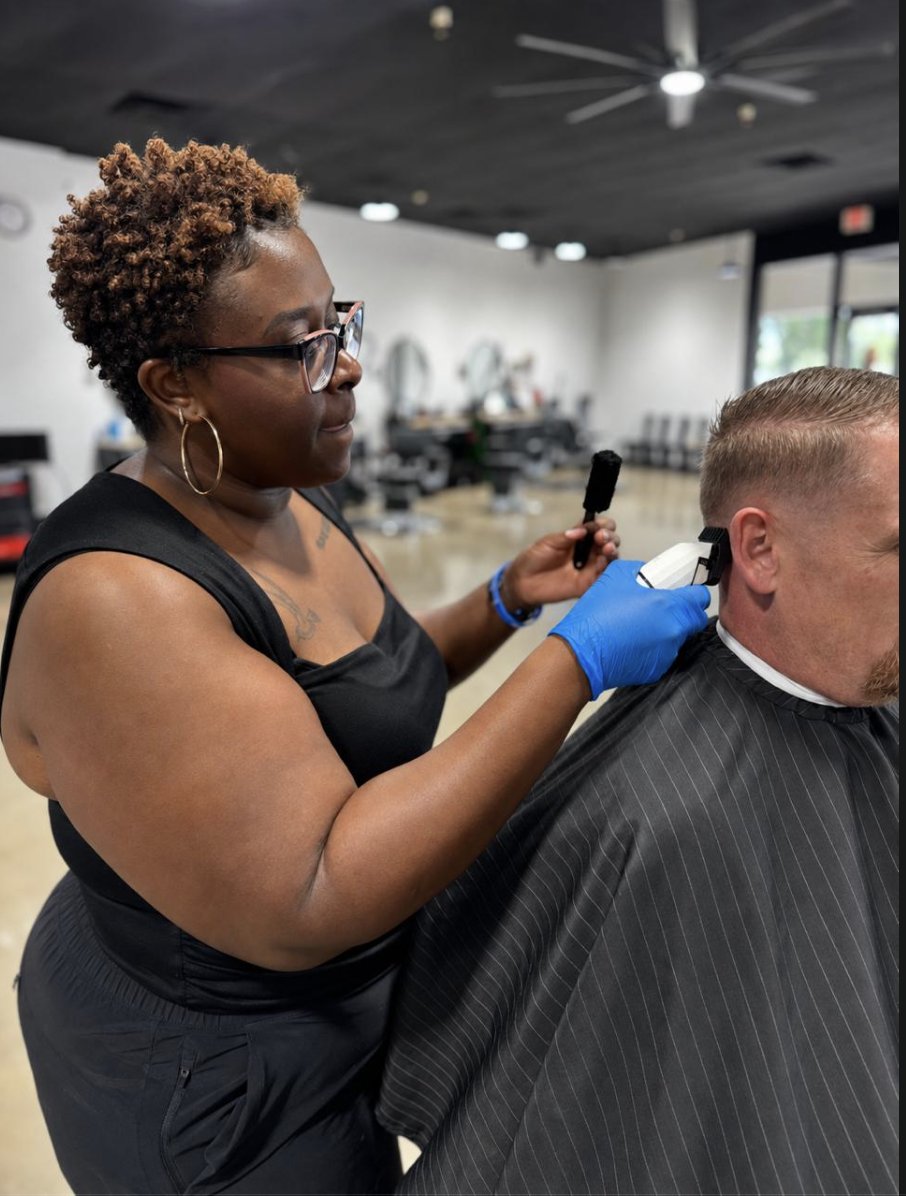 Barber taper fading a client's neckline with clippers at To the Nines Barbershop