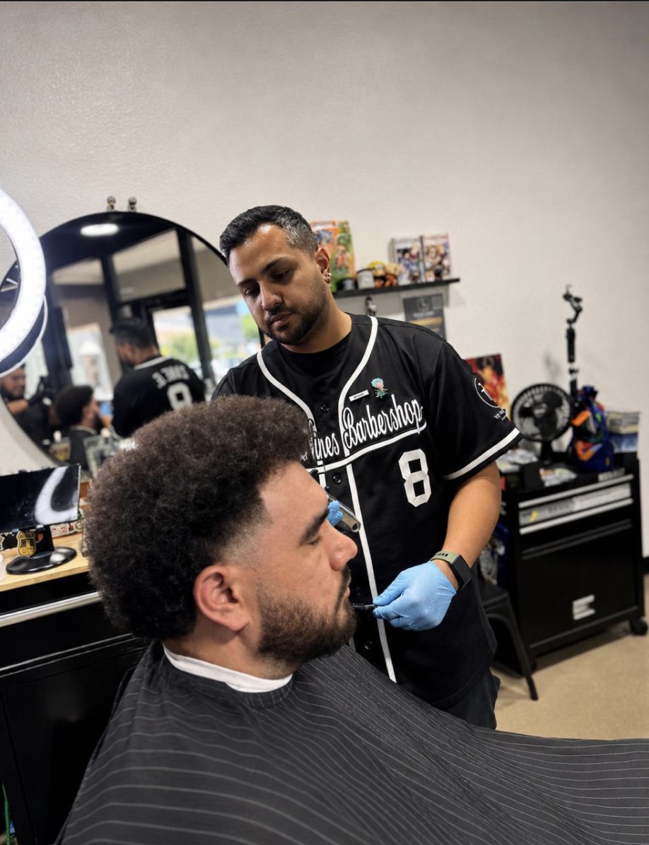 Barber lining up a beard in a To the Nines Barbershop jersey